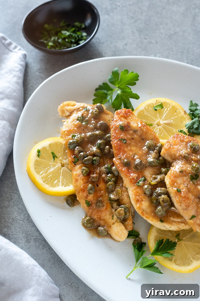 Deliciously Simple Chicken Piccata 9 Close-up of chicken piccata smothered in lemon caper butter sauce, garnished with fresh herbs.