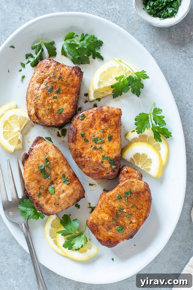 A vibrant platter showcasing boneless air fryer pork chops, beautifully golden, garnished with fresh lemon slices and chopped parsley, ready for a fresh, flavorful meal.