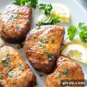 A high-angle shot of air fryer pork chops on a serving platter, garnished with fresh herbs, emphasizing their crispy texture.
