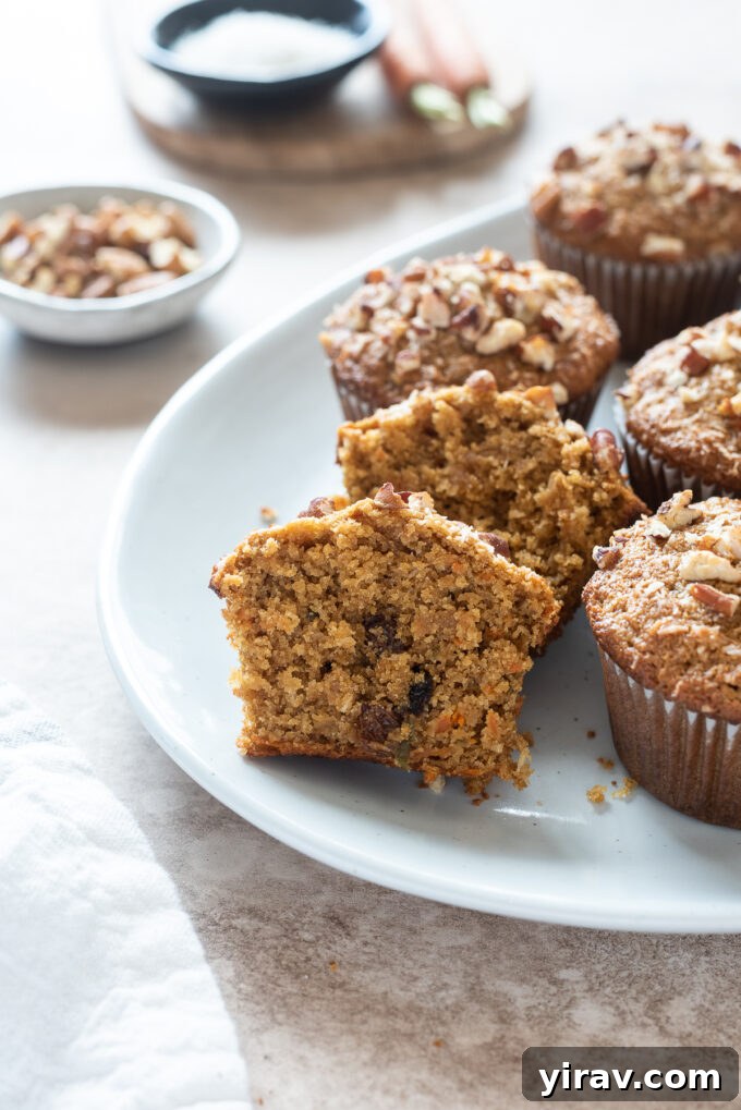 A gluten-free morning glory muffin, sliced in half, revealing its moist interior packed with carrot, apple, and coconut.