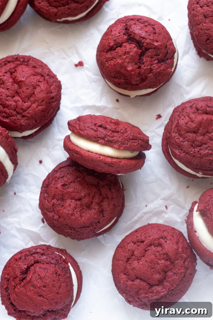 Freshly baked red velvet whoopie pie cookies cooling on parchment paper.