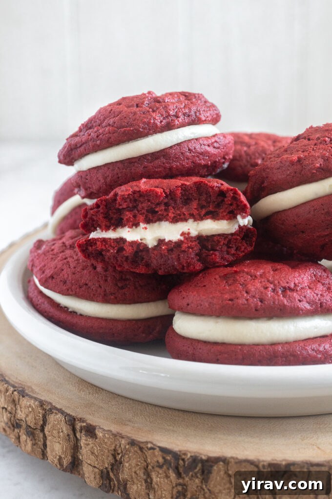 A red velvet whoopie pie cut in half, revealing the soft cookie texture and thick cream cheese filling.