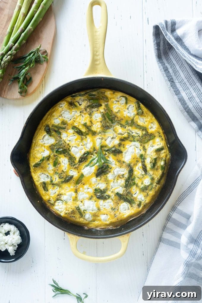 Vibrant green asparagus frittata in a rustic cast iron skillet, ready to be served for a delicious spring meal.