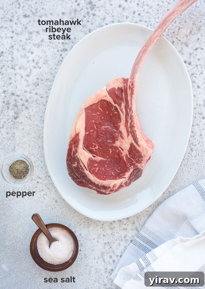 Simple ingredients for a Tomahawk steak recipe: a large steak, sea salt, and black pepper on a cutting board.