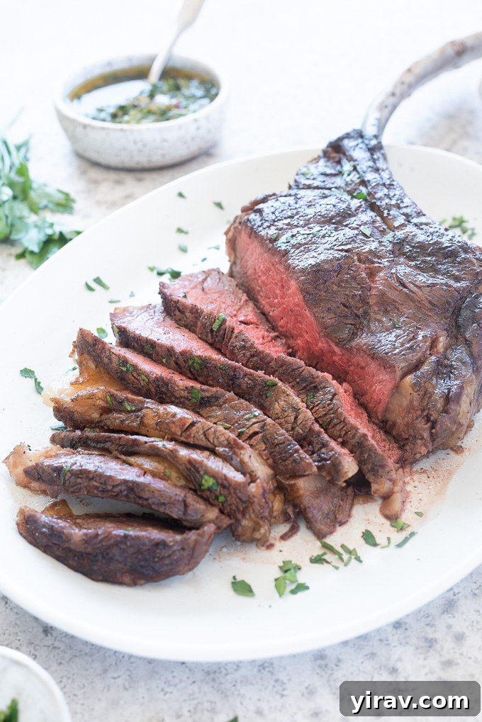 A perfectly grilled and sliced Tomahawk steak, showcasing its juicy interior, presented on a white platter.