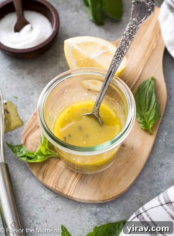 A jar of zesty homemade Italian dressing with a spoon, highlighting its vibrant herbs and spices.