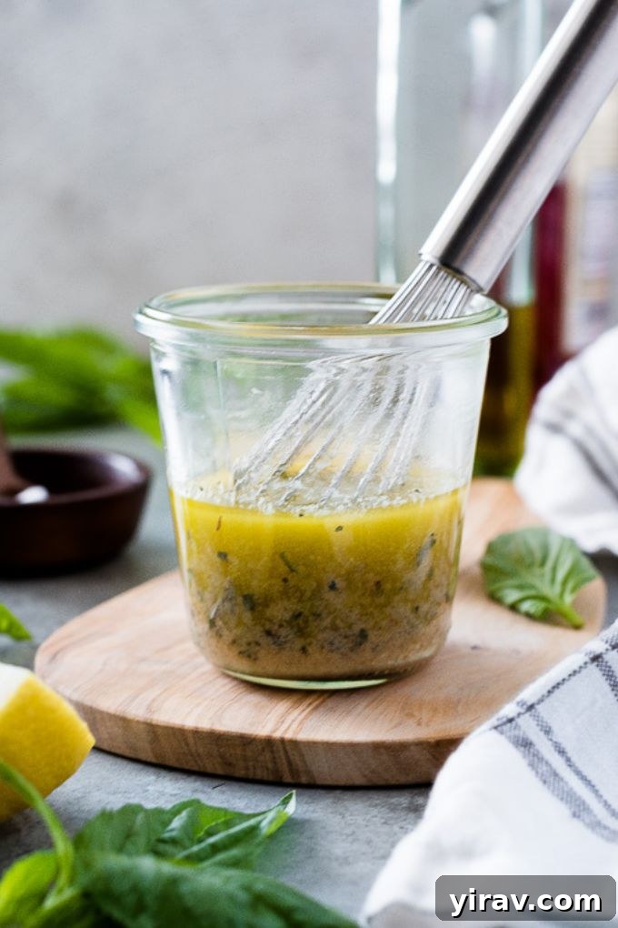 A jar of freshly made vinaigrette dressing with a small whisk, ready to be shaken and served on a delicious salad.