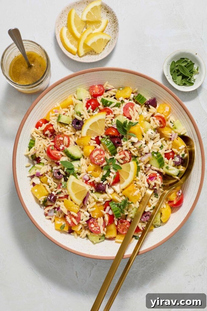 30 Refreshing Summer Salad Ideas 22 Greek Orzo Salad in a bowl, accompanied by salad servers.