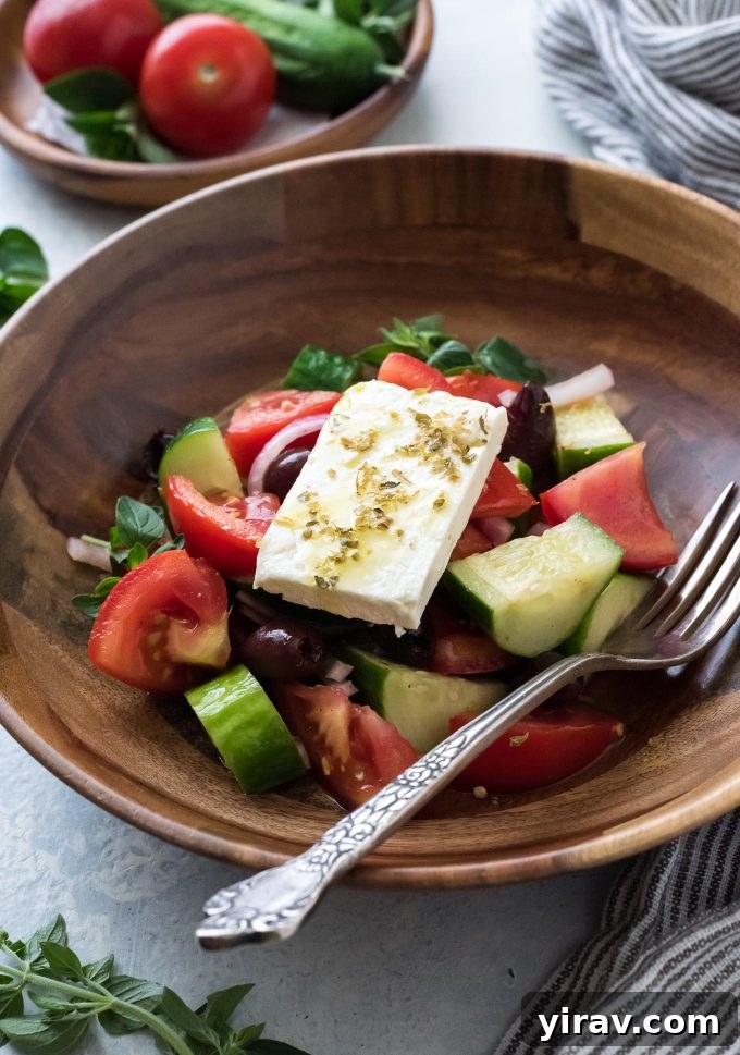 30 Refreshing Summer Salad Ideas 28 Horiatiki (Greek Village Salad) in a bowl with a fork, ready to be enjoyed.
