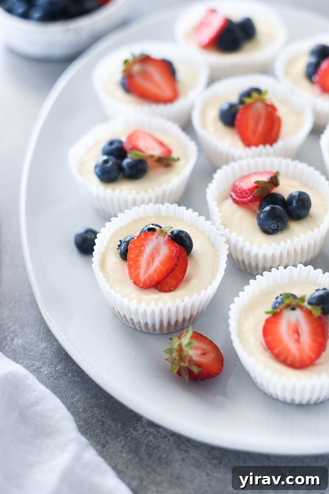 No-Bake Cheesecake Bites 6 A beautiful display of no-bake mini cheesecakes on a large platter, generously adorned with vibrant fresh berries, perfect for a summer gathering.