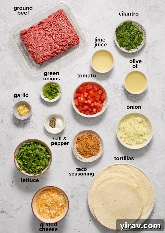 A selection of fresh ingredients for ground beef tacos, including ground beef, tortillas, lime, cilantro, and various vegetables.