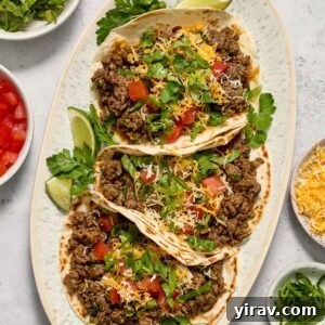 Easy Ground Beef Tacos on a white platter, garnished with lime and cilantro.