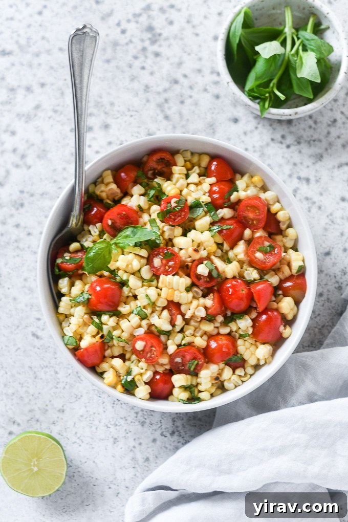 Vibrant Summer Corn and Tomato Medley 3 Close-up of corn and tomato salad in a white bowl, garnished with fresh basil leaves
