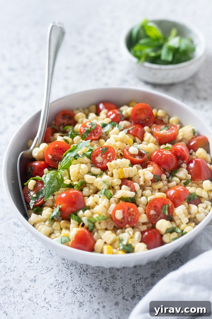Vibrant Summer Corn and Tomato Medley 7 Fresh corn and tomato salad in a serving bowl, garnished with a sprig of fresh basil