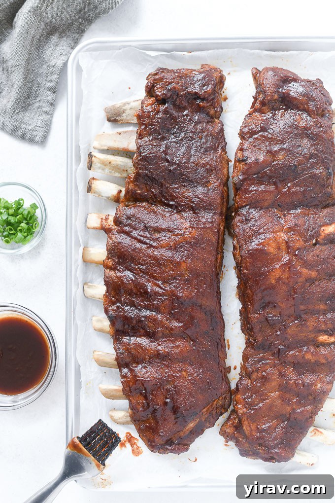 Instant Pot pork ribs neatly arranged on a baking sheet, brushed with sauce, ready to broil.