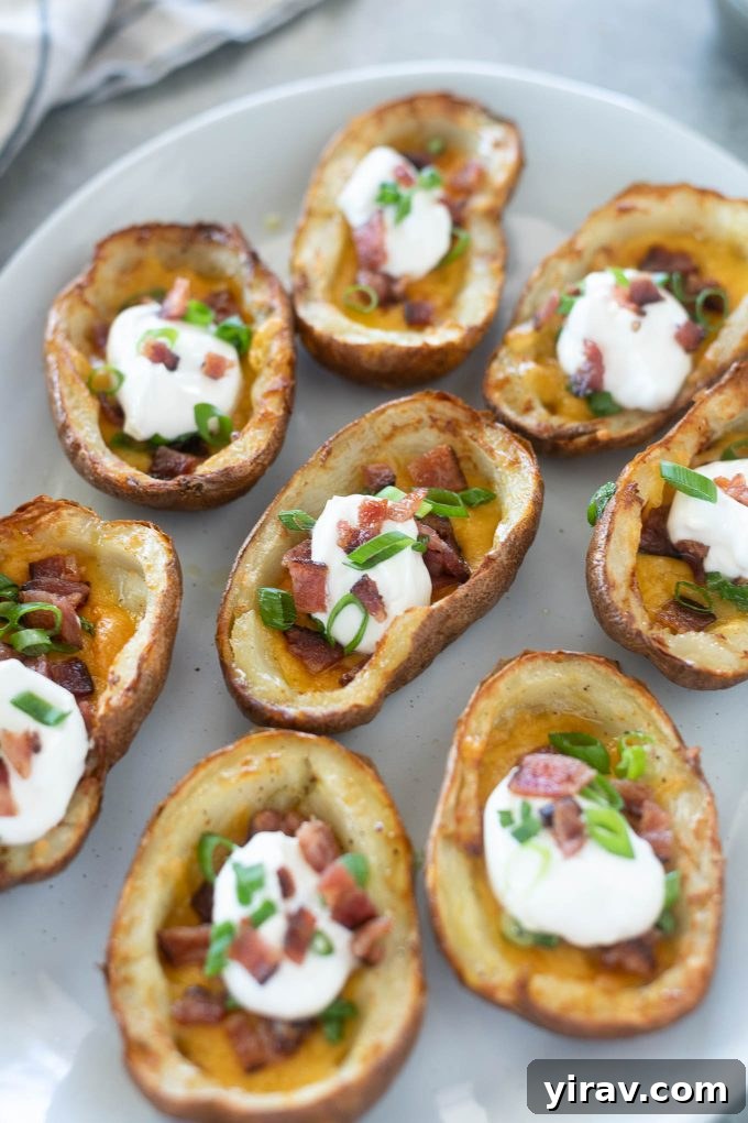Air fryer potato skins on a platter, garnished with fresh green onions and sour cream