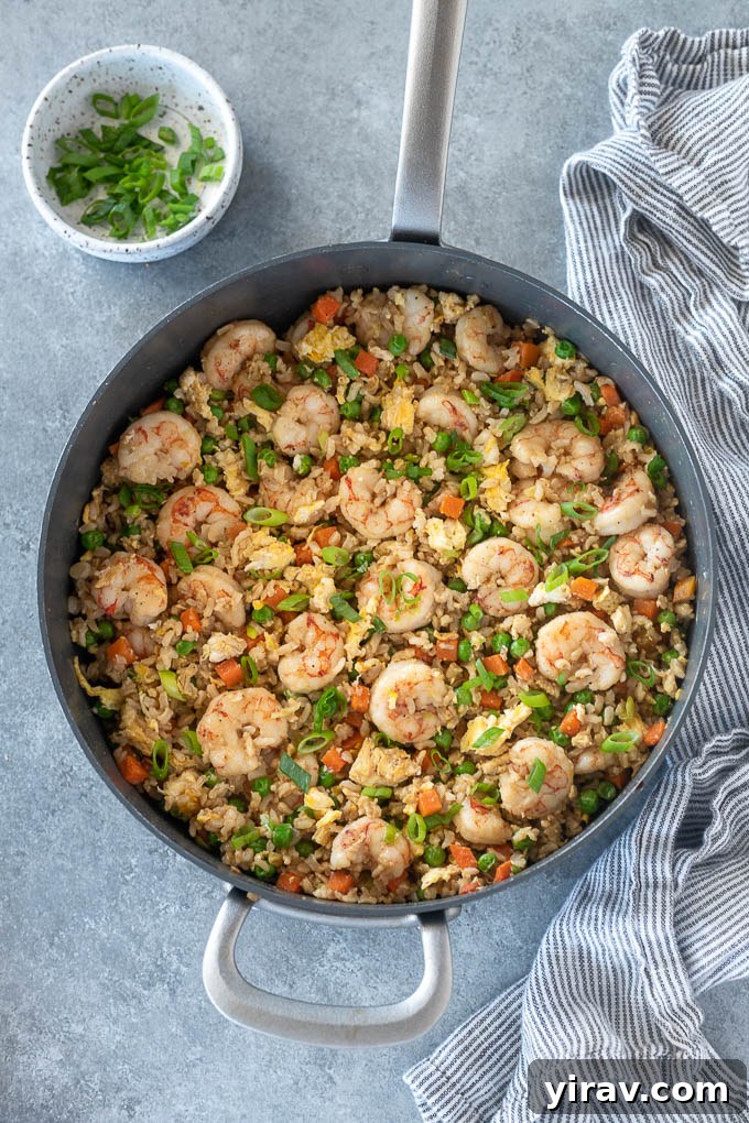 Pan of shrimp fried rice with fresh scallions for garnish