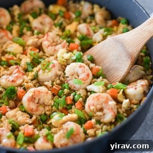 Wooden spoon digging into pan of shrimp fried rice