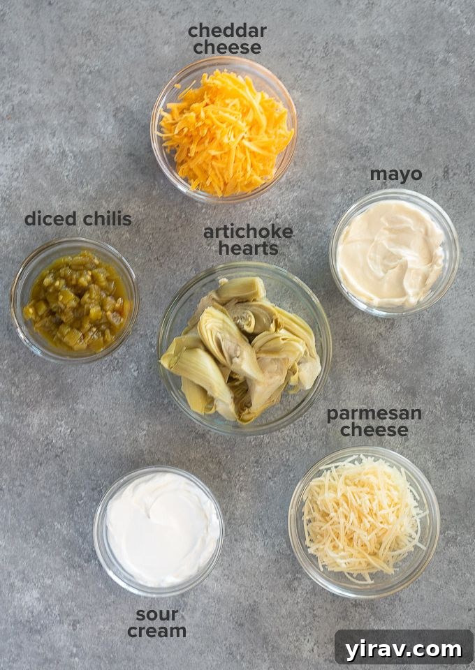 Irresistible Hot Artichoke Dip 4 A flat lay photograph of all the ingredients needed for hot artichoke dip: canned artichoke hearts, mayonnaise, sour cream, diced green chilis, grated cheddar cheese, and shredded parmesan cheese.