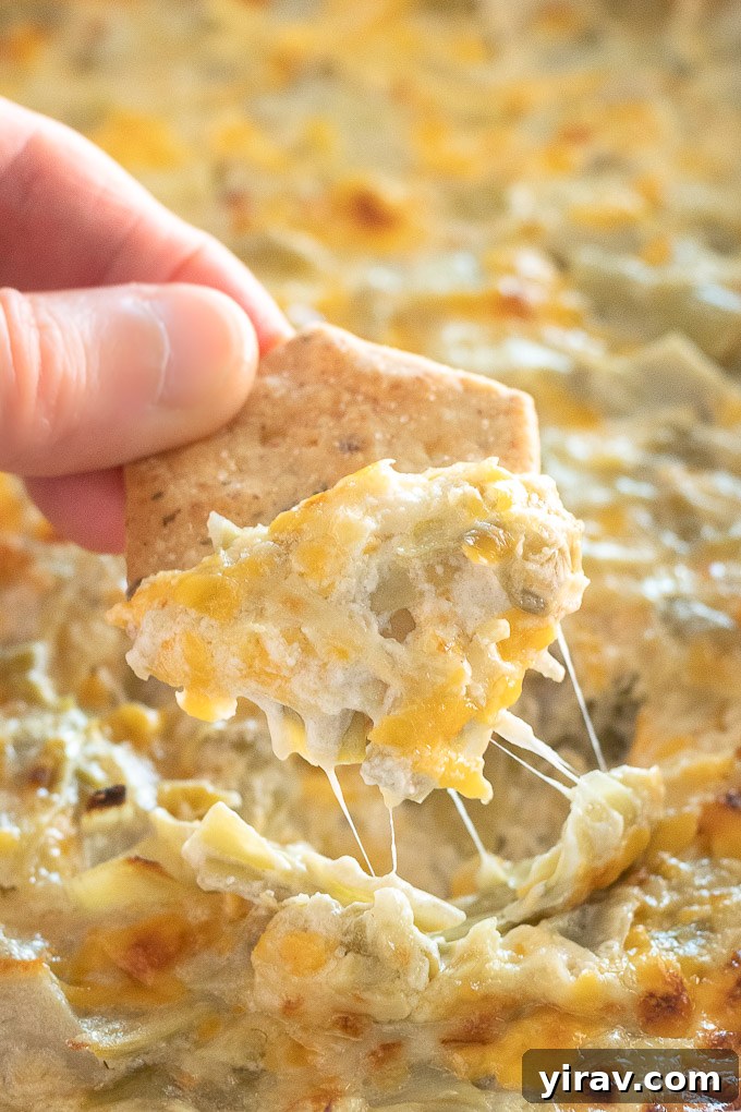 Irresistible Hot Artichoke Dip 7 A single cracker generously topped with hot artichoke dip, showing the creamy texture and melted cheese, ready for a bite.