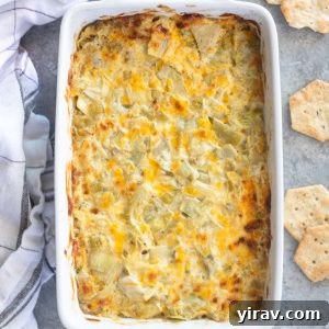 Hot artichoke dip in a baking dish with crackers