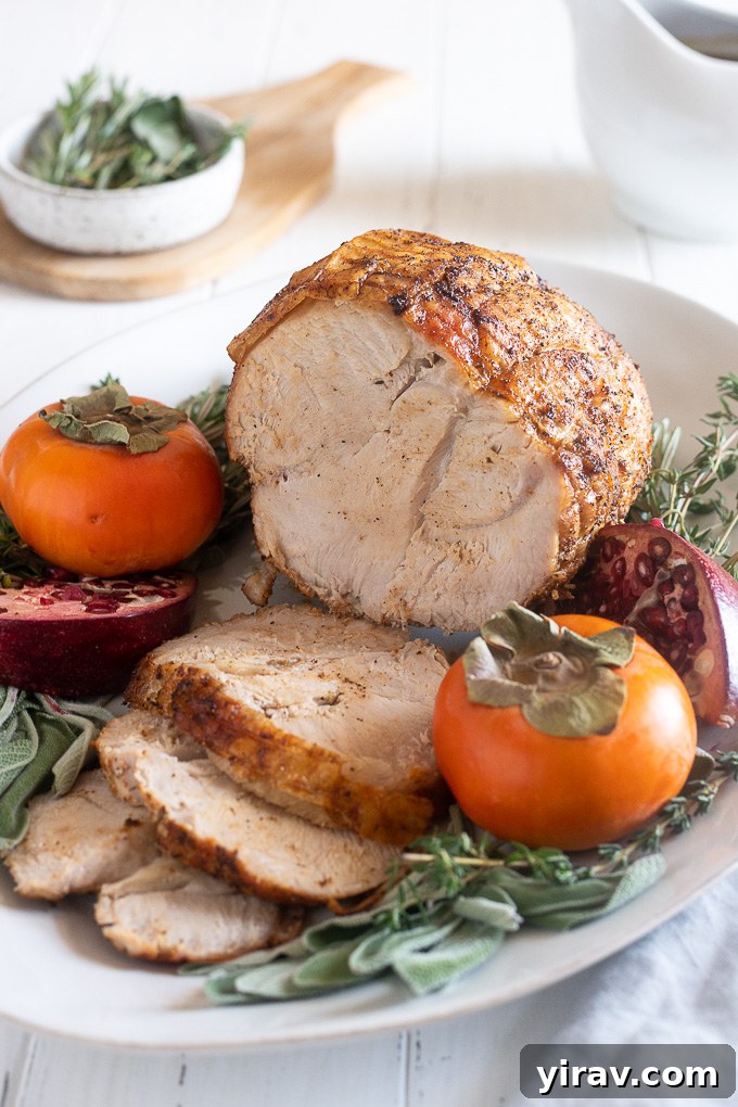 Beautifully roasted boneless turkey breast presented on a rustic platter, elegantly garnished with fresh rosemary, cranberries, and orange slices.