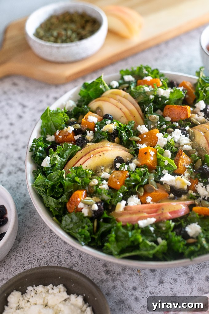 Close-up of a Fall Harvest Salad highlighting the roasted butternut squash and apple pieces mixed with kale and other toppings in a rustic bowl, ready to be served.