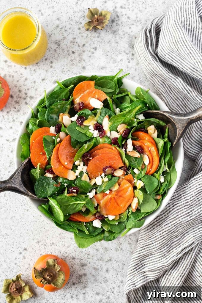 Persimmon Salad in a bowl with salad servers, highlighting the beautiful fall fruit.