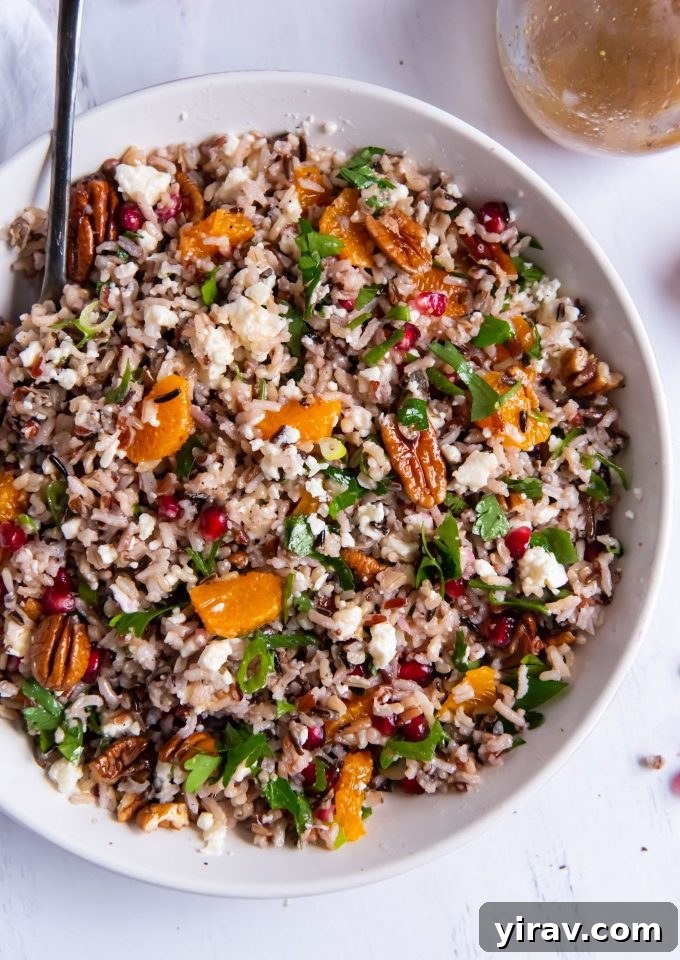 Wild Rice Salad in a white bowl with a serving spoon, highlighting the hearty grains and colorful ingredients.