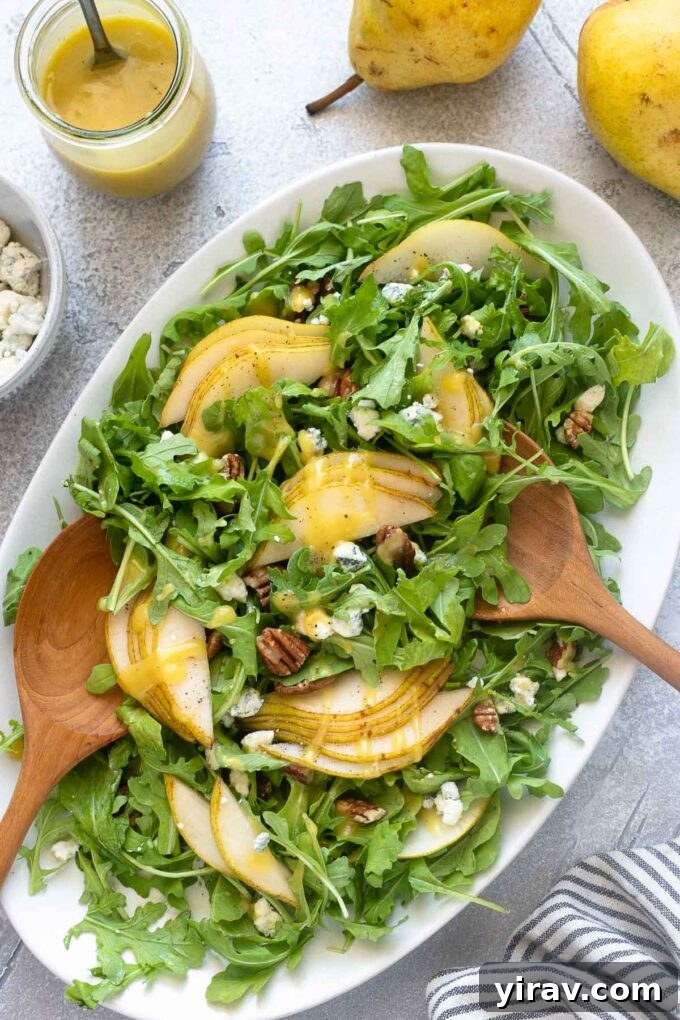 Arugula Pear Salad elegantly arranged on a platter with wooden salad servers.