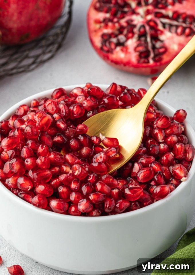 Spoon digging into bowl of pomegranate seeds