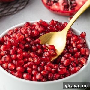 Spoon digging into bowl of pomegranate seeds