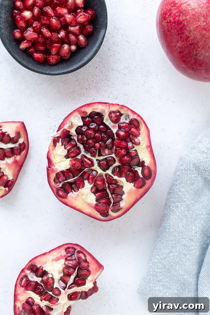 A vibrant red pomegranate neatly cut in half, revealing its intricate internal structure and gleaming arils.