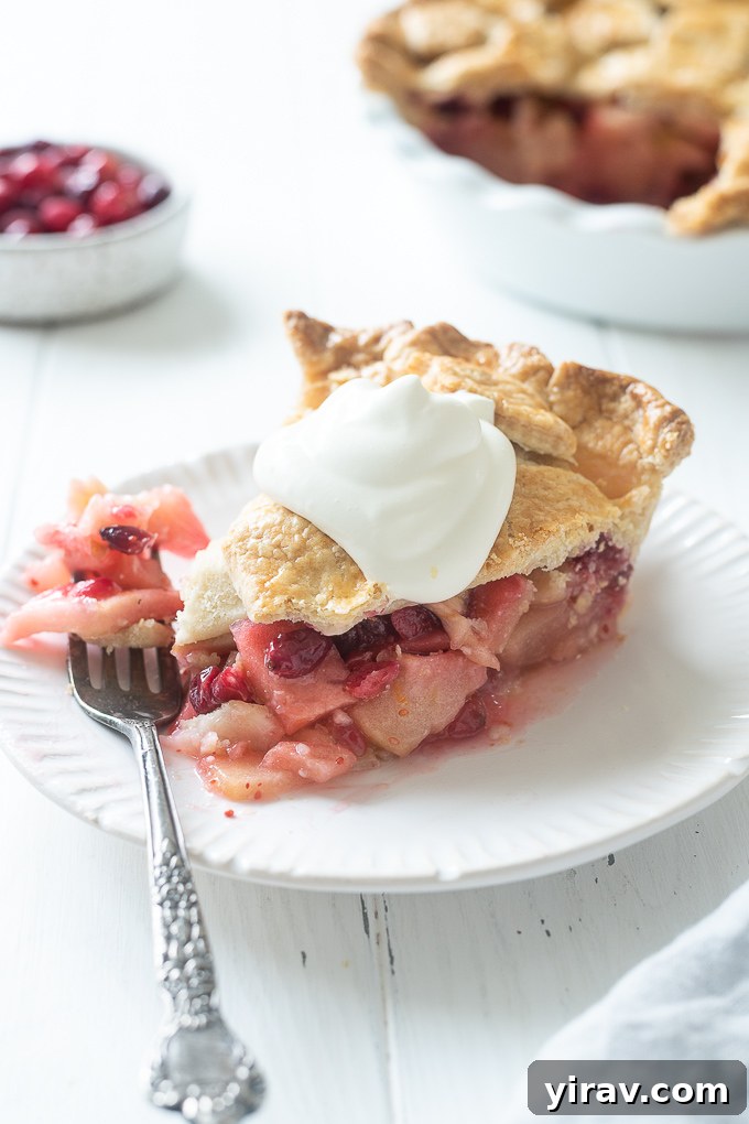 Plate with apple cranberry pie topped with whipped cream