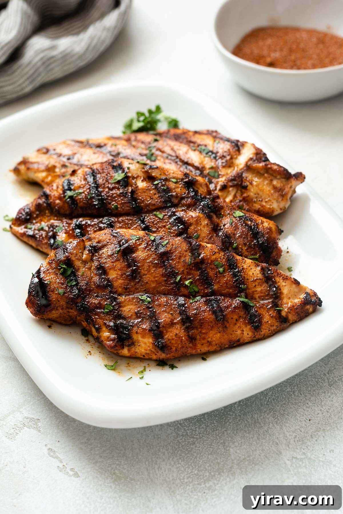 Smoky Sweet Chicken Coating 6 Perfectly grilled chicken breast, seasoned with BBQ rub, served on a pristine white plate, showcasing its golden crust.