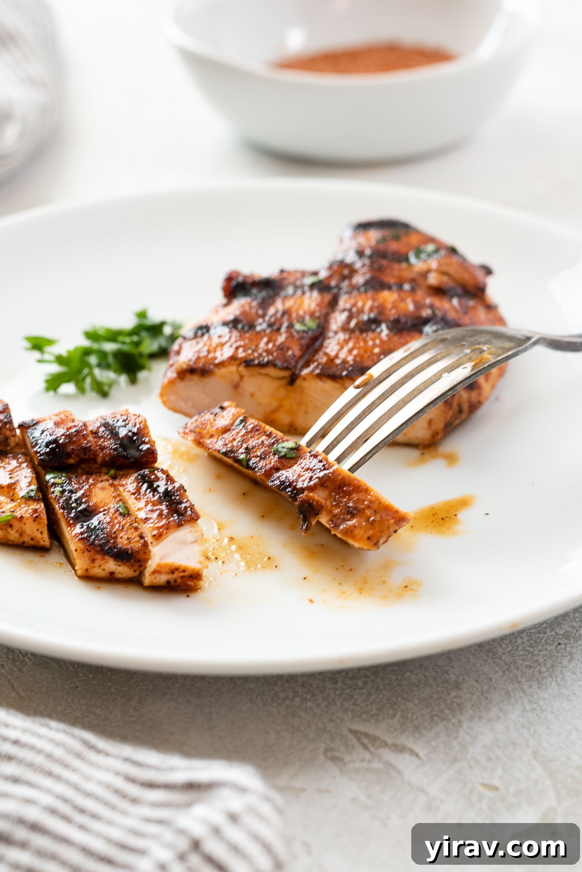 Smoky Sweet Chicken Coating 7 A slice of grilled chicken, perfectly seasoned with BBQ rub, held on a fork, ready to be enjoyed.