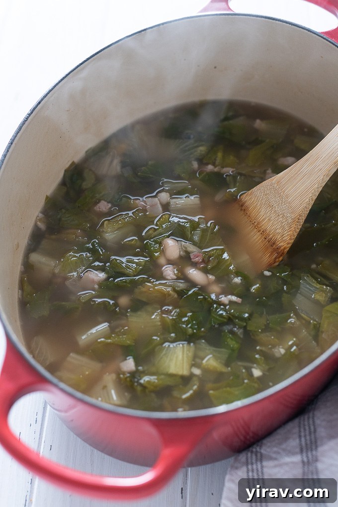 Escarole and bean soup generously portioned in a rustic Dutch oven, ready for serving.