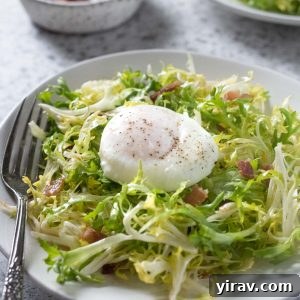Salade Lyonnaise on a plate of frisée lettuce, topped with a poached egg and crispy bacon