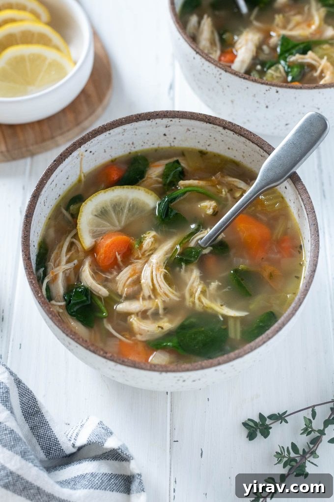 Chicken vegetable soup in a bowl, garnished with fresh herbs and lemon slices