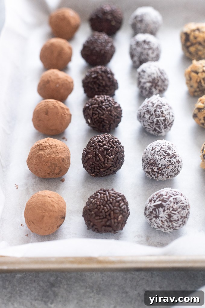 Variety of dark chocolate truffles rolled in different coatings, resting on a parchment-lined baking sheet.