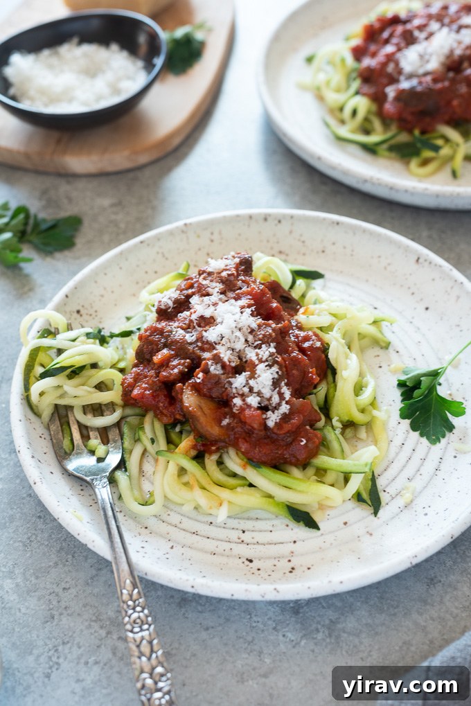A plate of zucchini noodles topped with generous amounts of homemade meat sauce and a sprinkle of Parmesan cheese.