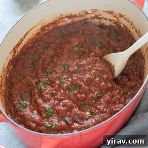 Homemade meat sauce simmering in a Dutch oven, garnished with fresh parsley.