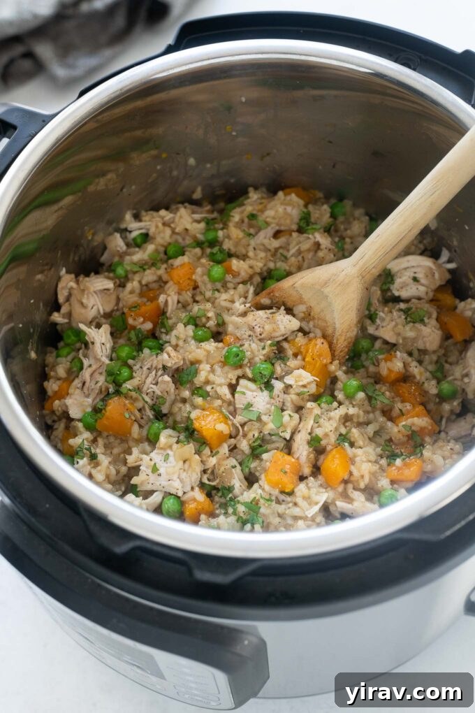 25+ Effortless Instant Pot Meals 9 Chicken and rice in the instant pot with wooden spoon digging in