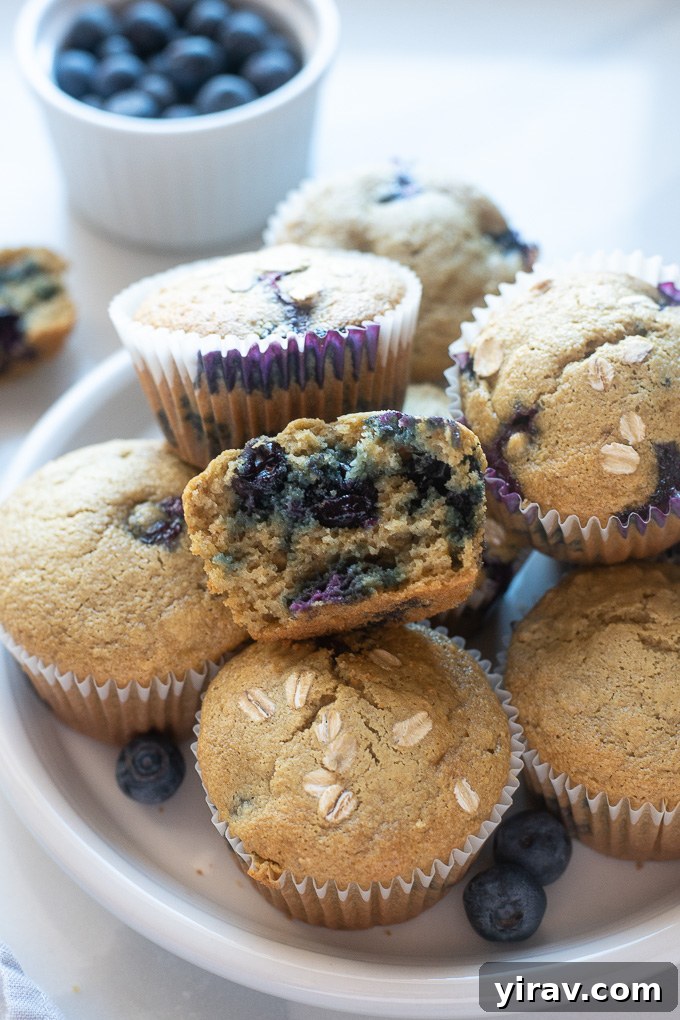Rustic Blueberry Oat Muffins 7 A healthy blueberry oatmeal muffin cut in half on a plate, revealing its moist interior and scattered blueberries.