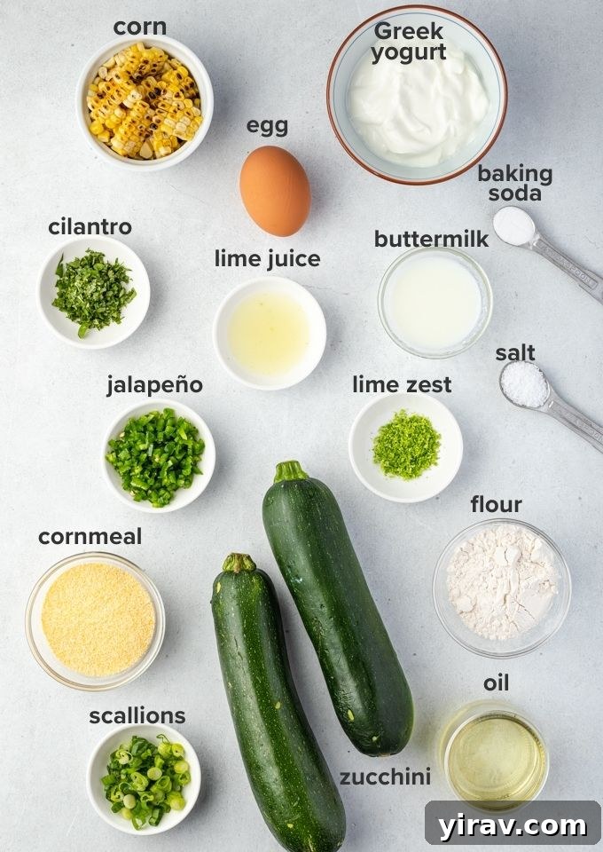 Fresh ingredients for zucchini fritters, including grated zucchini, corn, flour, egg, and green onions, alongside yogurt ingredients like cilantro, lime, and jalapeño.