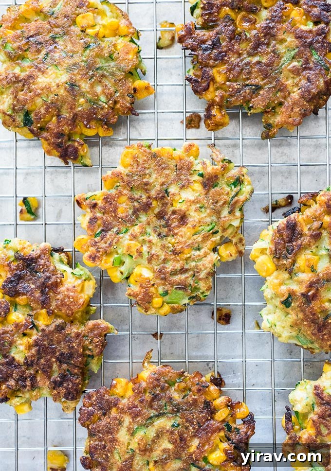 Freshly fried zucchini and corn fritters cooling on a wire rack.