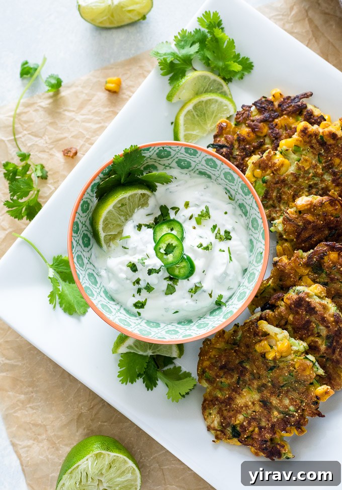 Close-up of crispy zucchini fritters with a bowl of cilantro lime Greek yogurt dip, garnished with fresh cilantro.