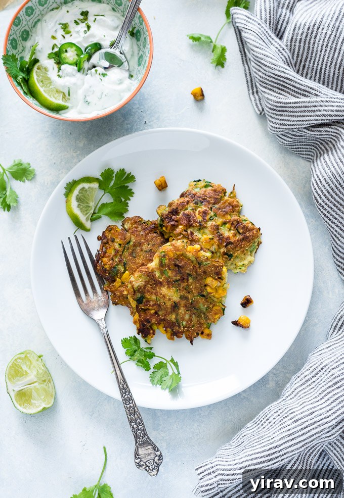 Plate of zucchini and corn fritters with a side of cilantro lime yogurt, seen from above.