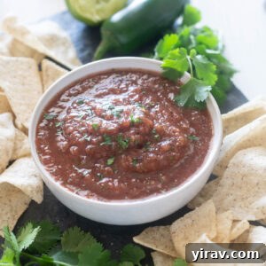 Restaurant style salsa in a bowl with chips and cilantro around it