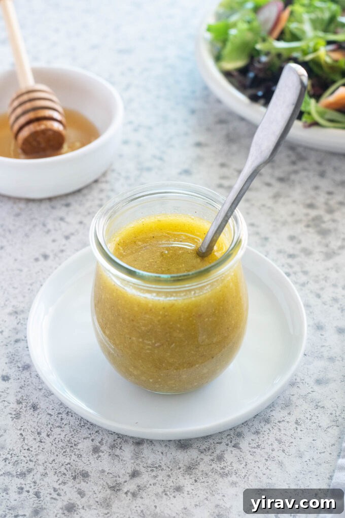 Homemade Honey Mustard Dressing in a glass jar with a spoon, ready to be served over a salad.